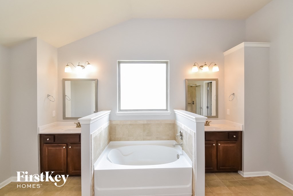 a bathroom with a large tub and a sink and a mirror