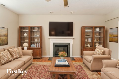 A living room with a fireplace and a television mounted above it.