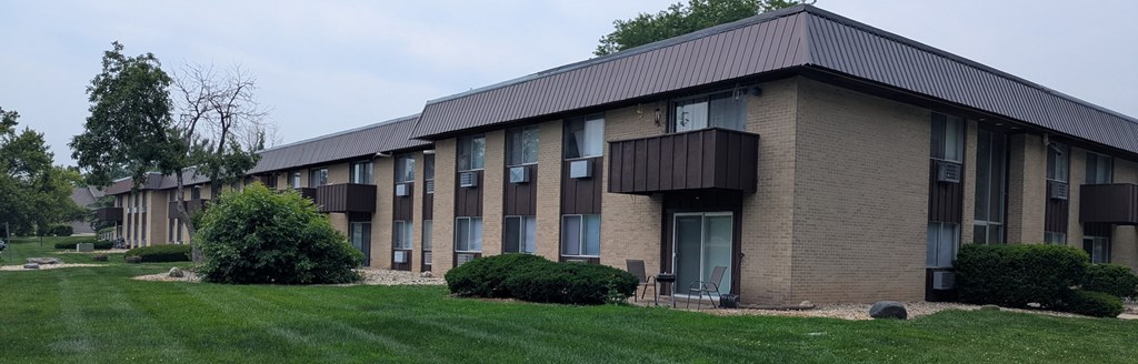 A long building with a lot of windows and bushes in front.