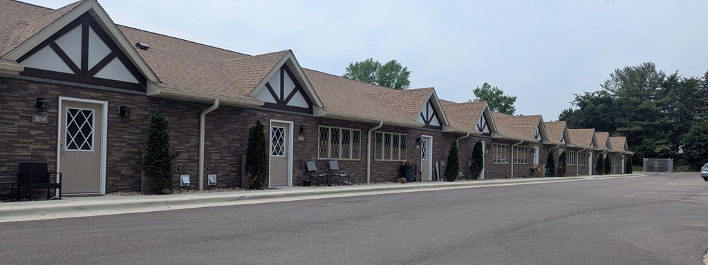 A long building with a brown roof and a grey door.