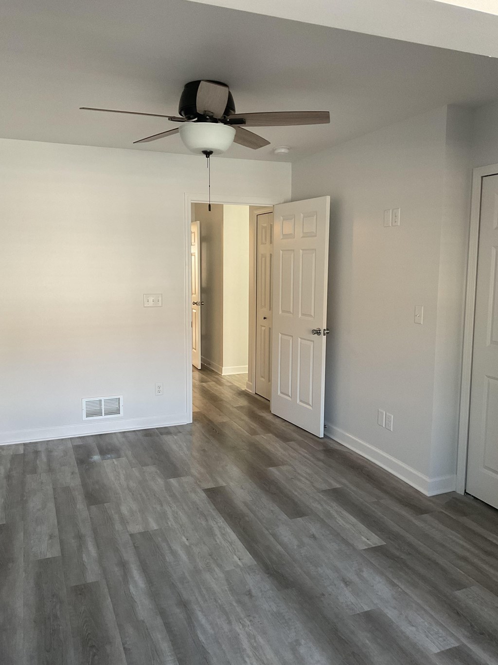 A room with a ceiling fan and a doorway leading to another room.