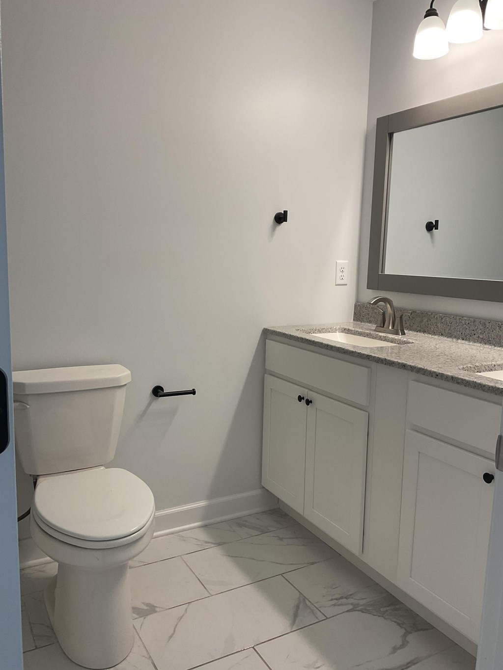 A white toilet sits in a bathroom next to a sink and a mirror.