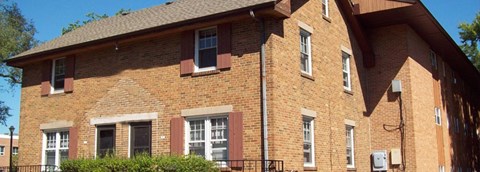 A red brick building with a black fence in front.