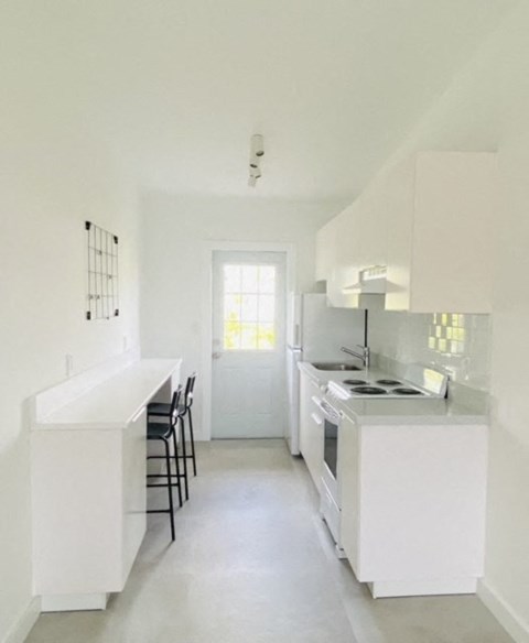 an empty kitchen with white cabinets and a counter top