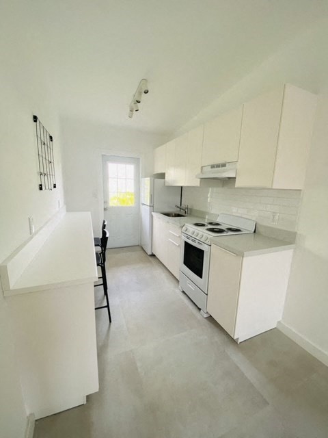 an empty kitchen with white cabinets and a stove