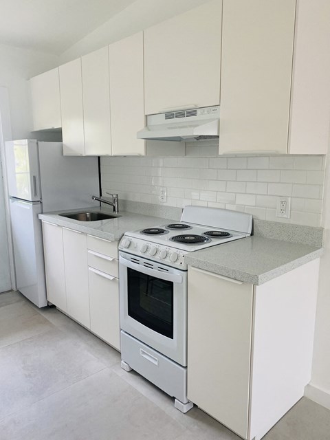 an empty kitchen with white appliances and white cabinets