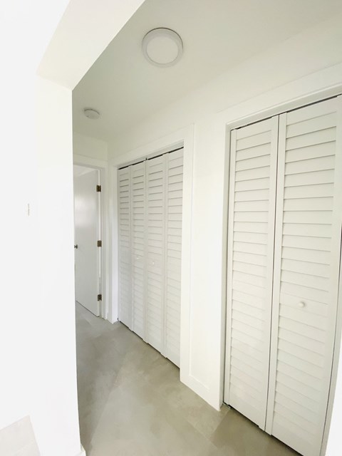 a hallway with white shuttered closet doors in a home