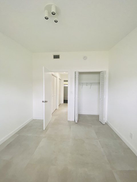 an empty room with white walls and a hallway with white closets