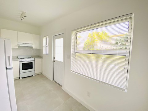 a kitchen with a large window and a white stove and refrigerator