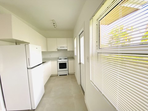 a kitchen with white cabinets and a refrigerator and a window