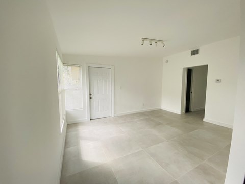 an empty living room with white walls and a tile floor