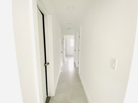 a white hallway with a black door and white walls