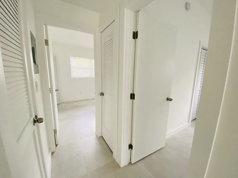 an open hallway with white doors and a white tile floor