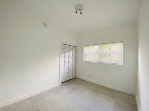 the living room of a home with white walls and a window