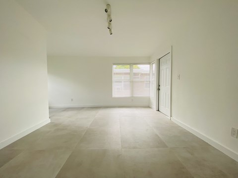 an empty living room with white walls and tile floors