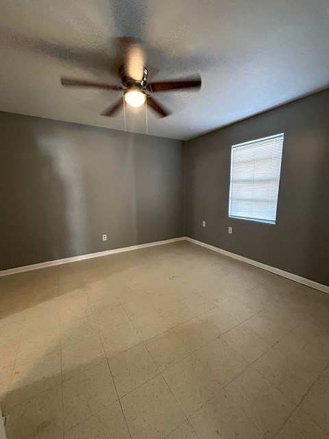 A room with a ceiling fan and a window with blinds.