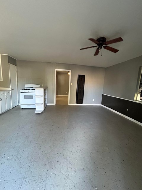 A room with a ceiling fan and a white appliance.