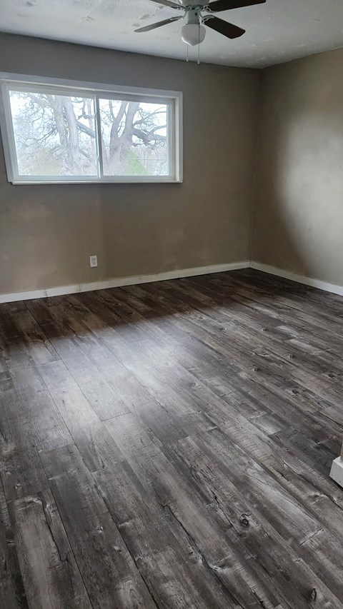 an empty room with wood floors and a window