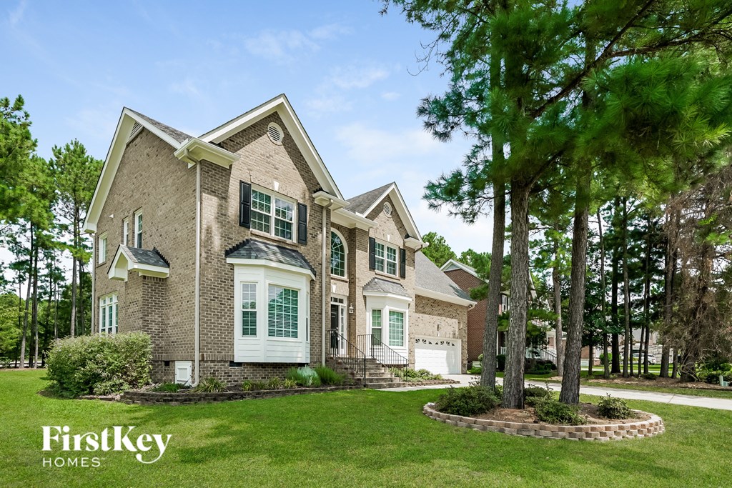 a large brick house with green shutters and trees