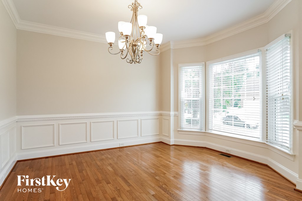 a dining room with white wainscoting and a chandelier