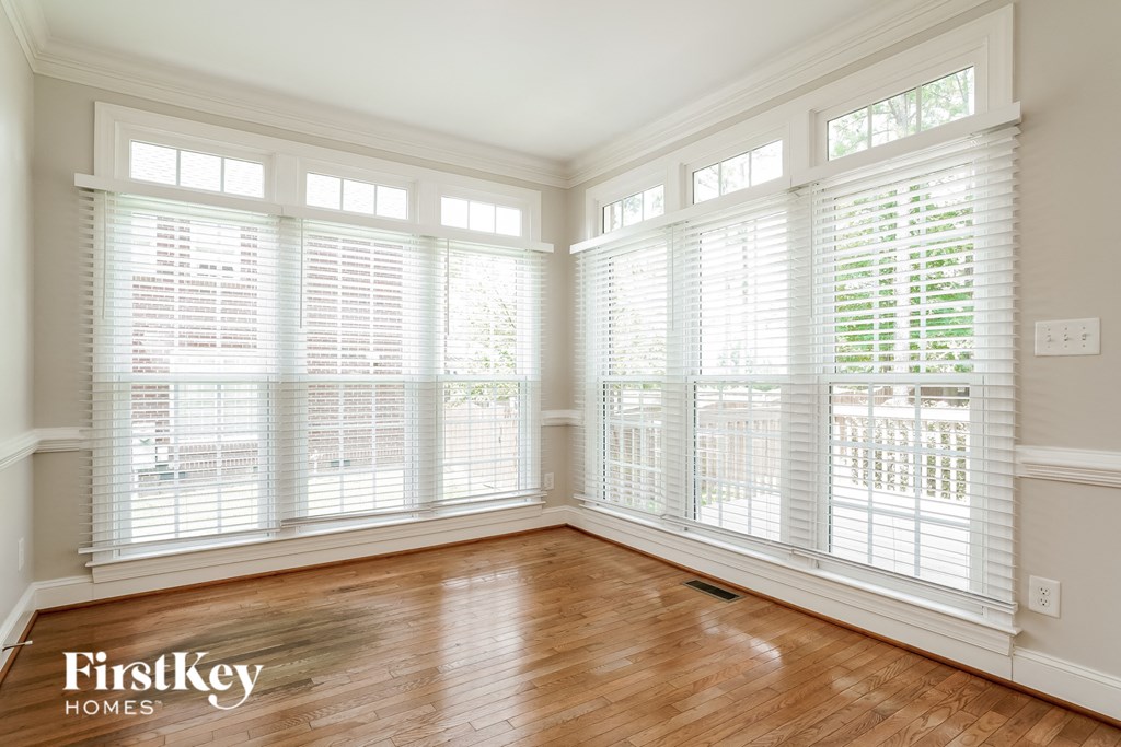 a living room with wood floors and large windows with white plantation shutters