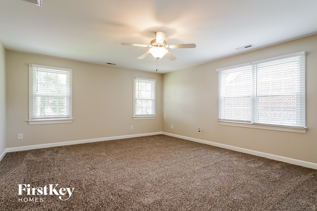 an empty living room with a ceiling fan and two windows