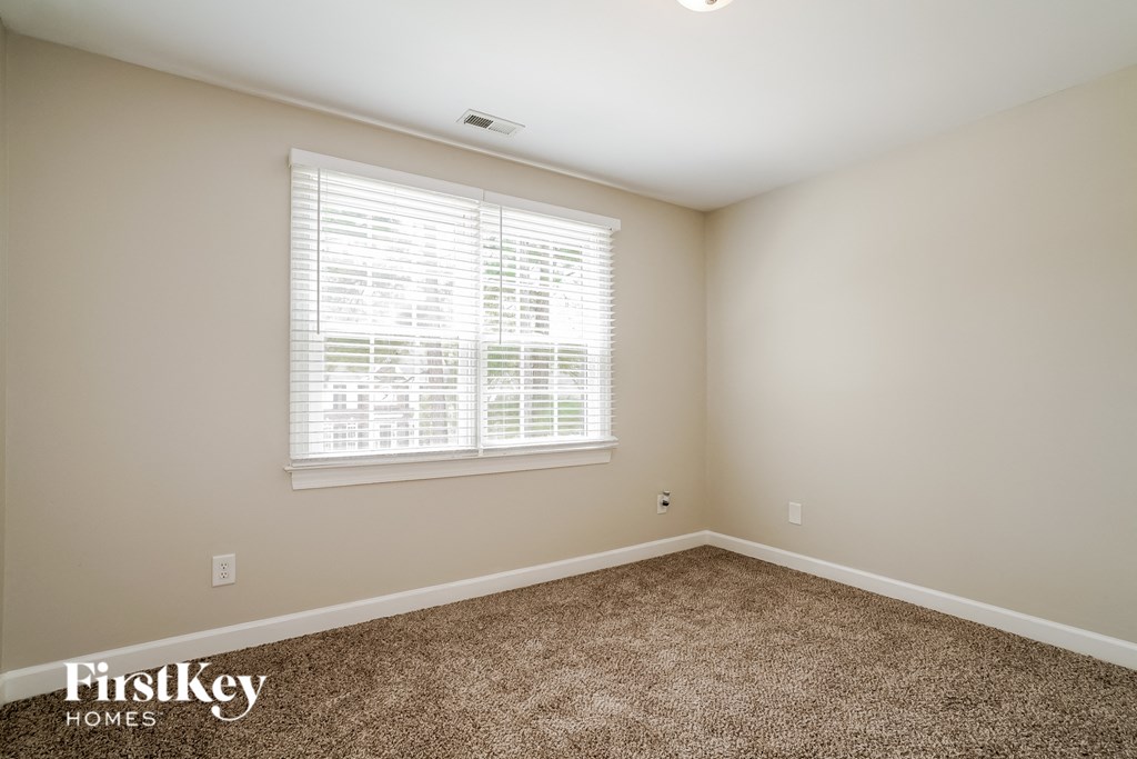 a bedroom with carpet and a large window