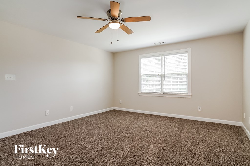 the master bedroom has carpet and a ceiling fan