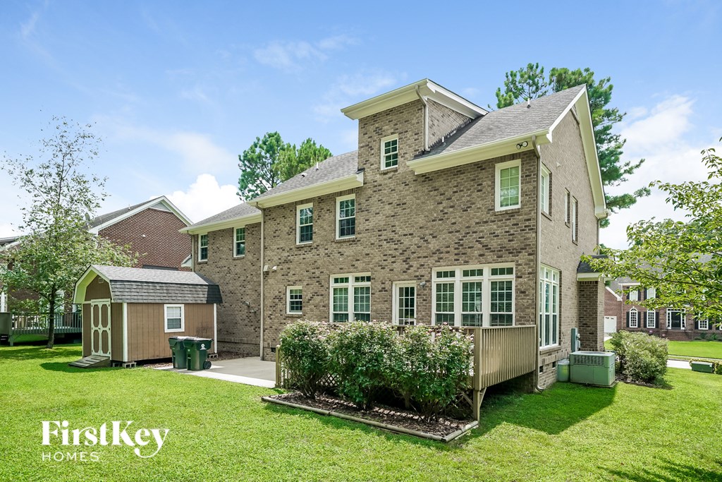 a side view of a brick house with a yard and a wooden deck