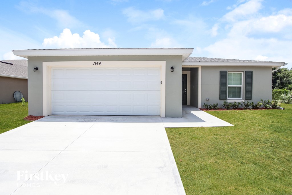a white house with a white garage door and a lawn