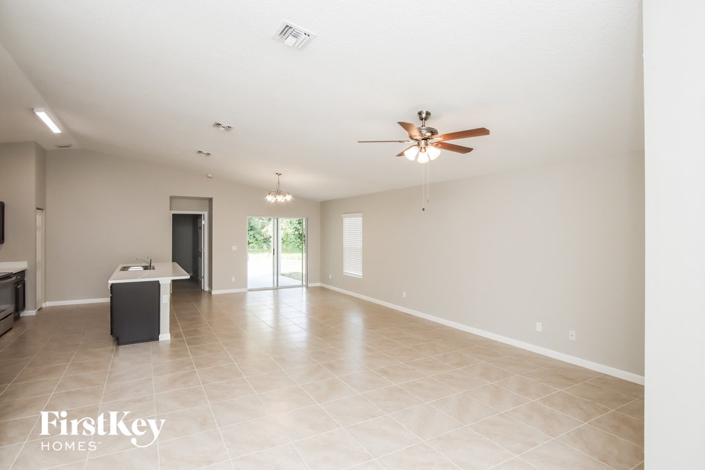 an empty living room and kitchen with a ceiling fan