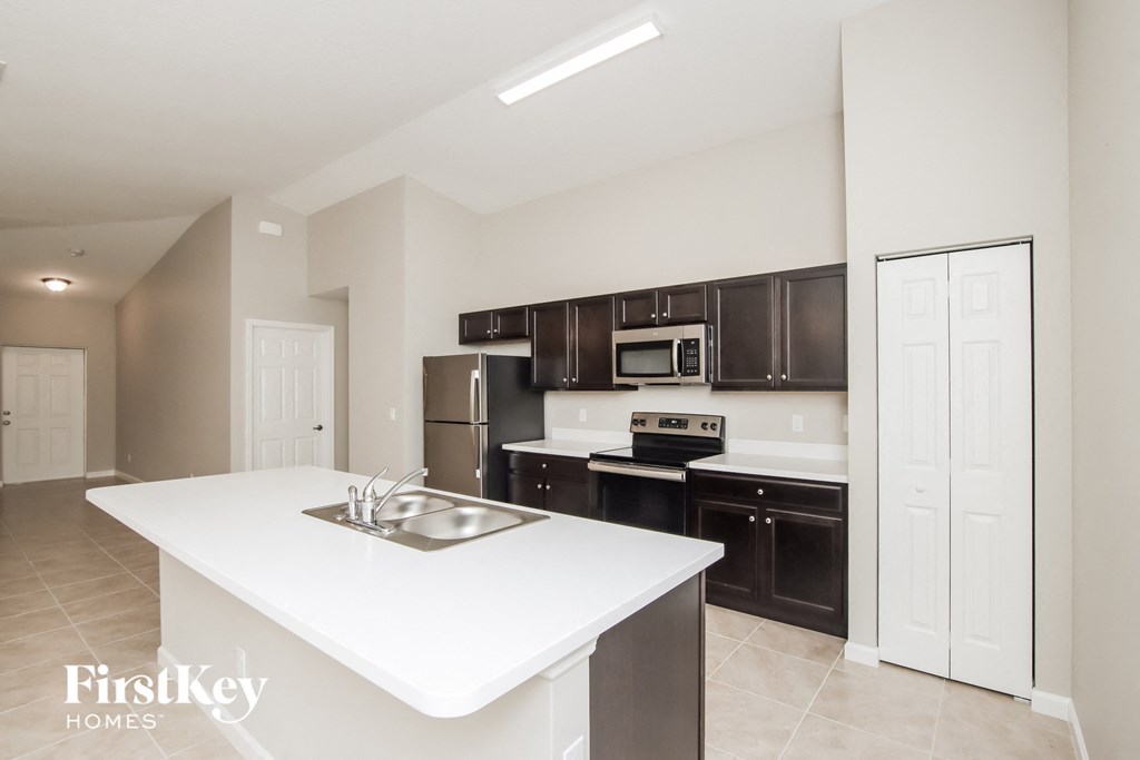a white kitchen with black cabinets and stainless steel appliances