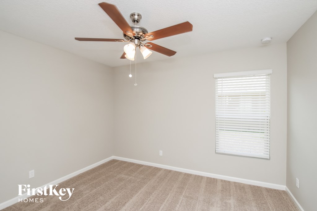 an empty room with a ceiling fan and a window