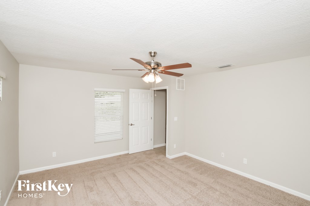 a living room with a ceiling fan and a door to a closet