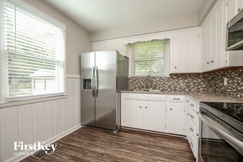 A kitchen with a stainless steel refrigerator and wooden floors.