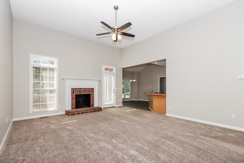 an empty living room with a fireplace and a ceiling fan