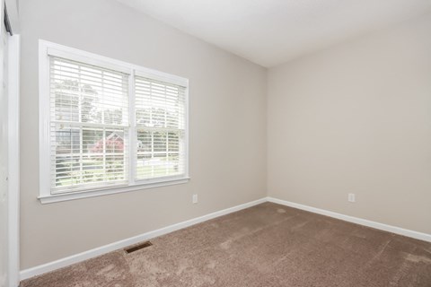 an empty bedroom with a large window and carpeting