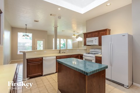 A kitchen with a white refrigerator and a glass island.