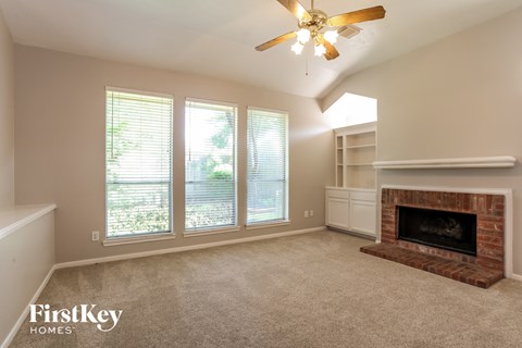 A living room with a fireplace and a ceiling fan.