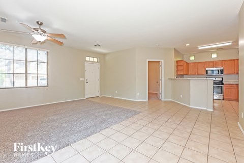 A spacious living room with a fan and a rug on the floor.