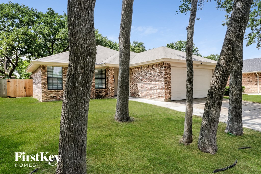 a house with a yard and trees in front of it