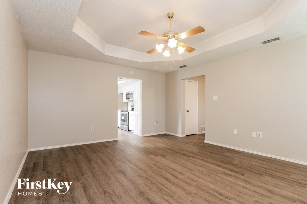 the living room and dining room of an empty house with a ceiling fan