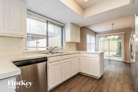 a kitchen with white cabinets and stainless steel appliances and a large window