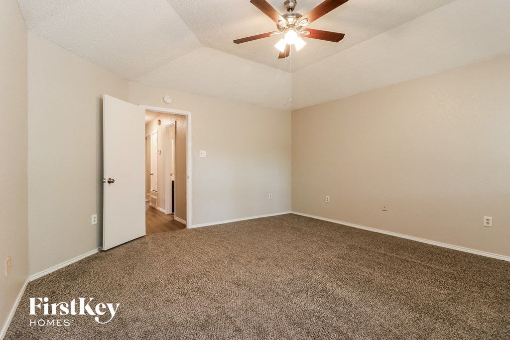 the spacious living room with carpeting and a ceiling fan