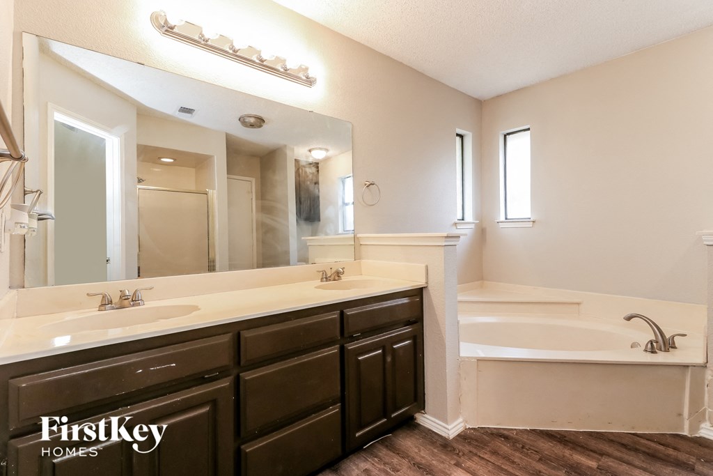 a bathroom with two sinks and a tub and a large mirror