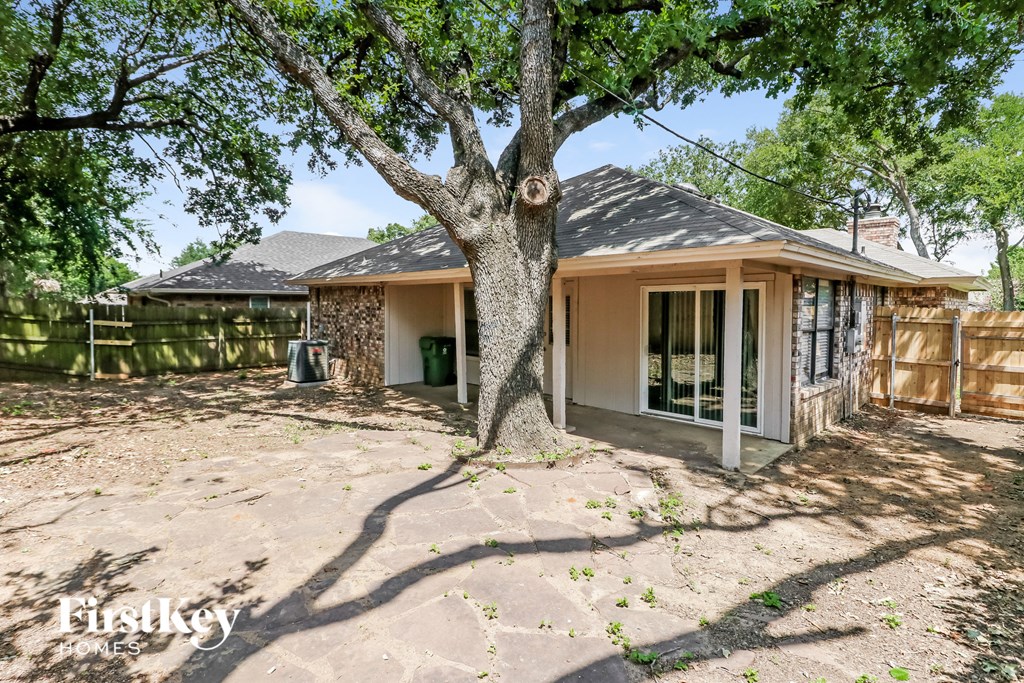 a backyard with a tree and a house with a fence