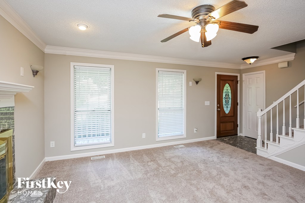 an empty living room with a ceiling fan and a staircase