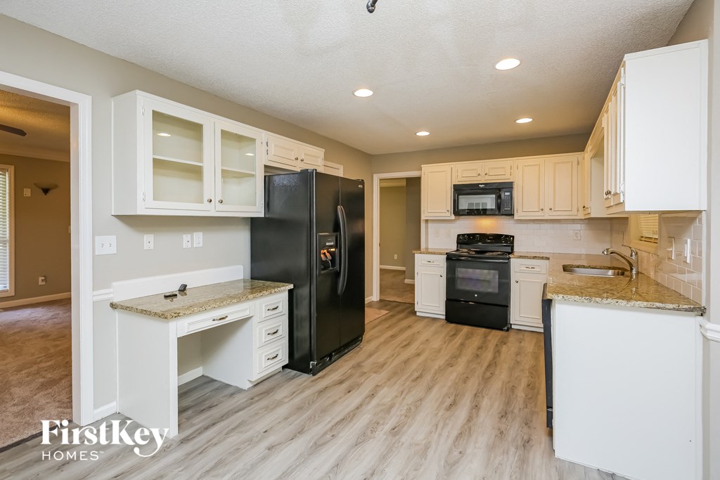 a kitchen with white cabinets and a black refrigerator