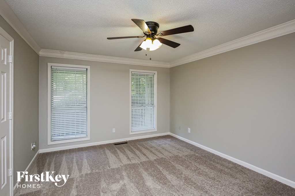 an empty living room with a ceiling fan and window