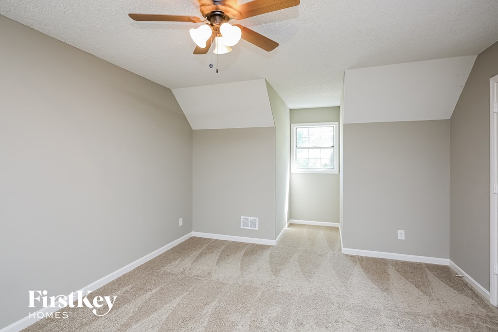 the spacious living room with ceiling fan and carpeting